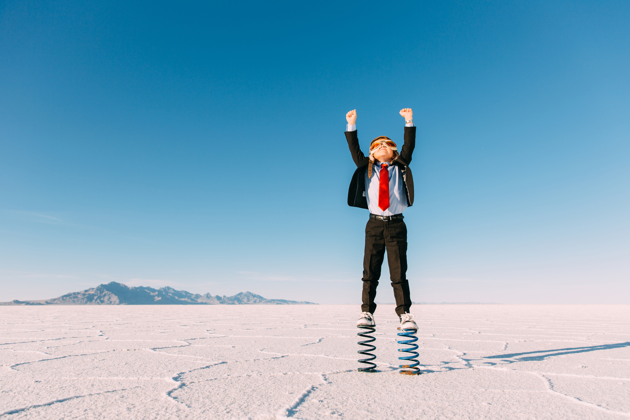 Un joven empresario vestido con traje de negocios, gorra de vuelo y gafas se encuentra en manantiales en el desierto de Utah.  empresa en crecimiento para nuevas empresas saas