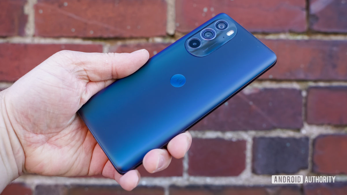 Motorola Edge Plus 2022 parte trasera en ángulo en la mano contra un ladrillo