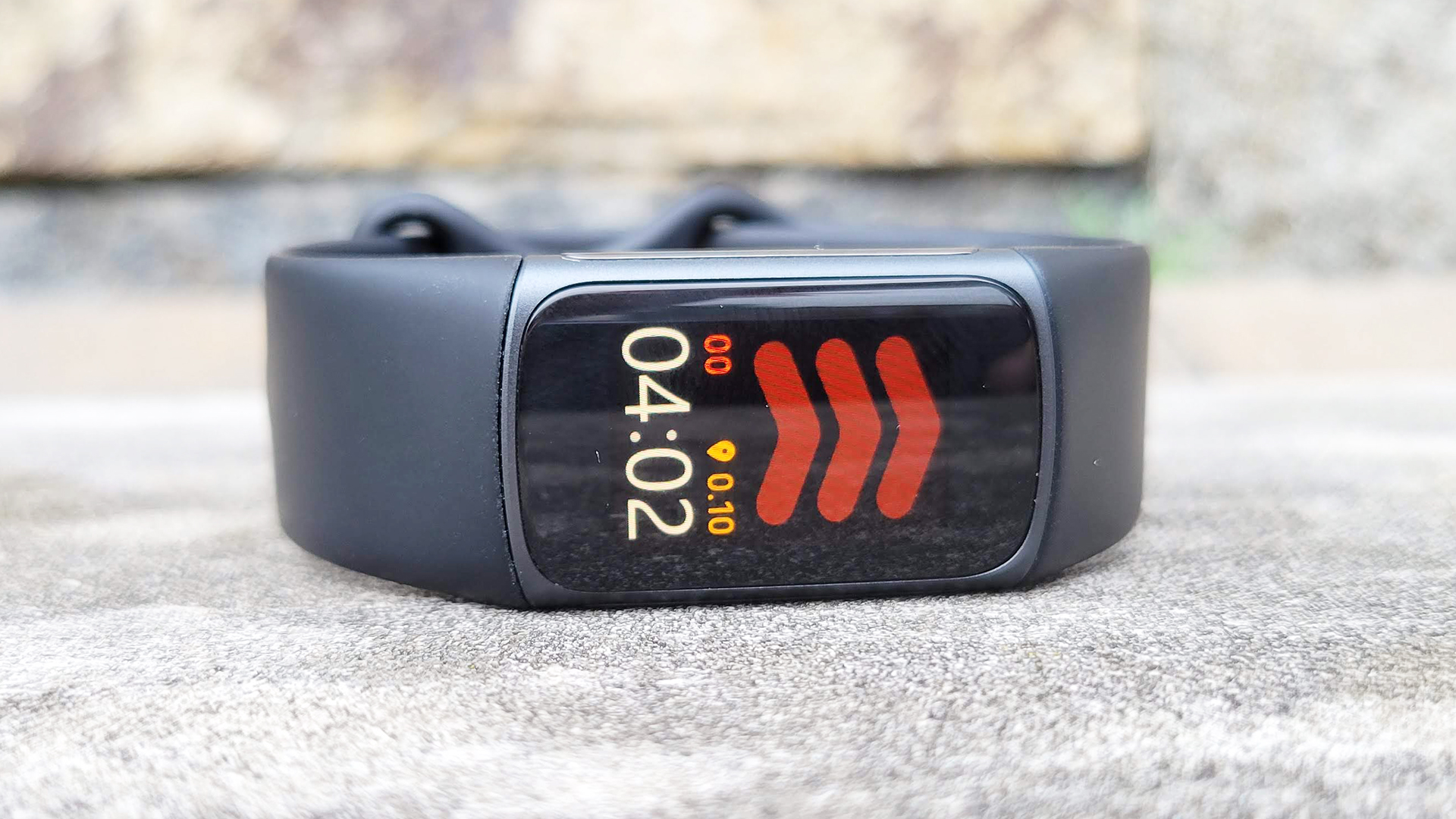Un Fitbit Charge 5 descansa de lado sobre una superficie de cemento.