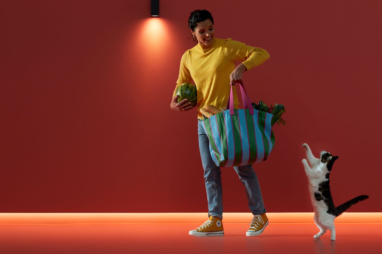 Mujer y gato pasando junto a un semáforo.
