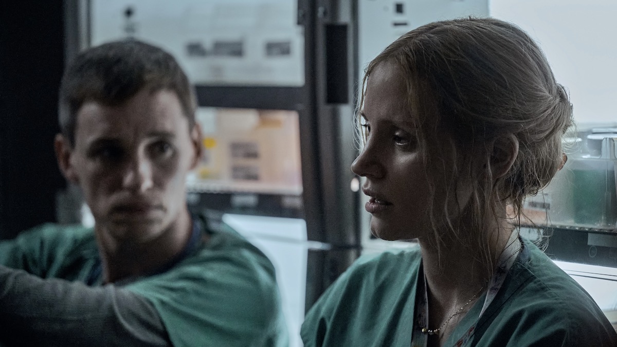 Dos enfermeras, Eddie Redmayne como Charlie Cullen y Jessica Chastain como Amy Loughren, películas de misterio en Netflix, se sientan juntas en el suelo en The Good Nurse